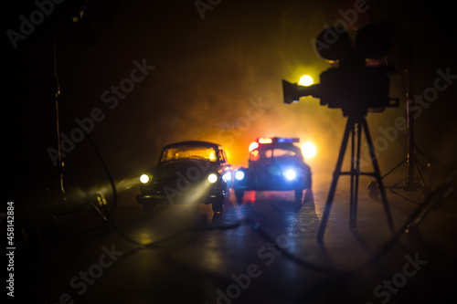 Action movie concept. Police cars and miniature movie set on dark toned background with fog. Police car chasing a car at night. Scene of crime accident. © zef art