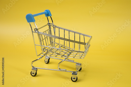 Empty Groceries trolley on yellow background