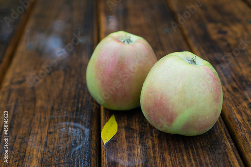 Autumn apples in the rain. Organic apples on the wooden table. Raindrops on green apples. Northern spy