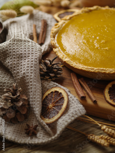 Stylish composition of American pie, citrus slices, cinnamon sticks, pine cones, wheat ears. Low angle view. Yellow-brown tones. Close-up. There are no people in the photo. Halloween, Thanksgiving.