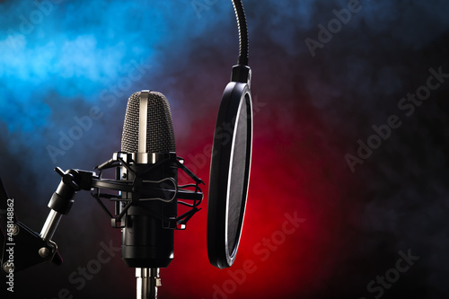 Studio microphone and pop filter on red-blue background. Minimalism. There are no people in the photo. Close-up. Recording studio, vocals. music, concert, purity of sound, debate.
