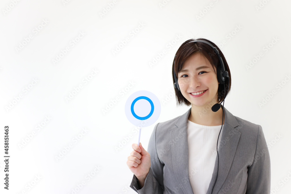ヘッドセットを着け〇札を持つ女性社員 ヘッドセットを着け〇札を持つ女性社員