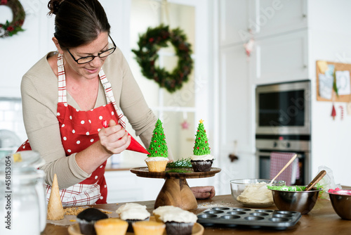 Woman decorating a cupcake in a kitchen