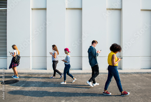 Slika na platnu Young adults using smartphones as they are walking outdoors