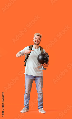 Male tourist with globe on color background