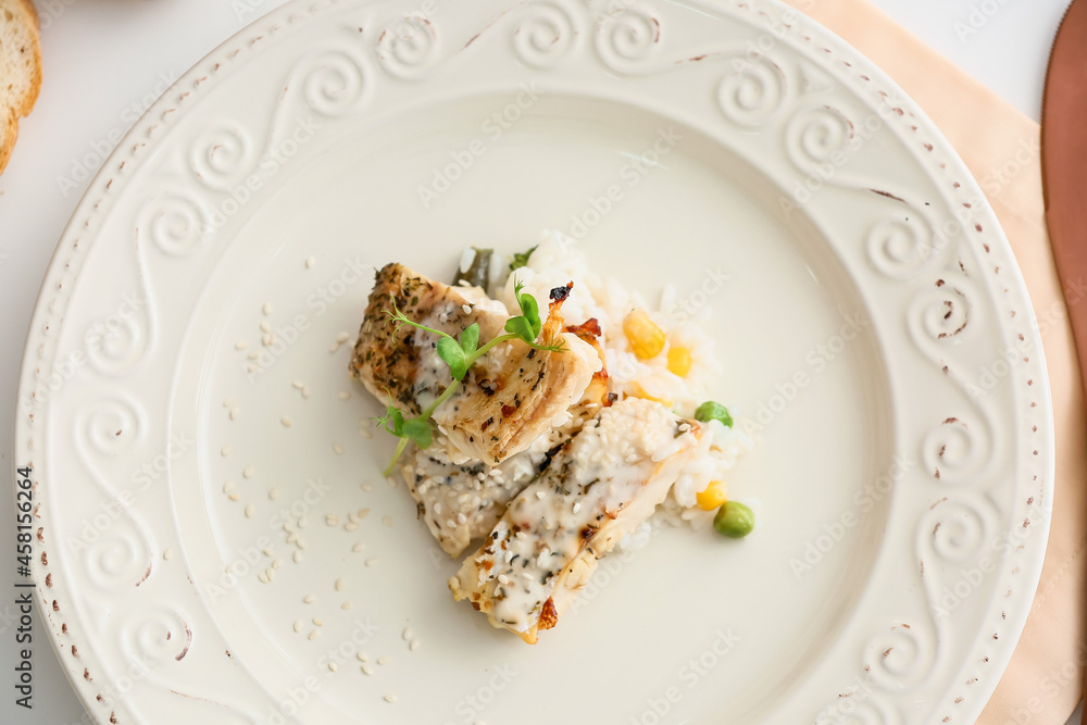 Plate with tasty baked cod fillet, rice and vegetables on table in restaurant Plate with tasty baked cod fillet, rice and vegetables on table in restaurant