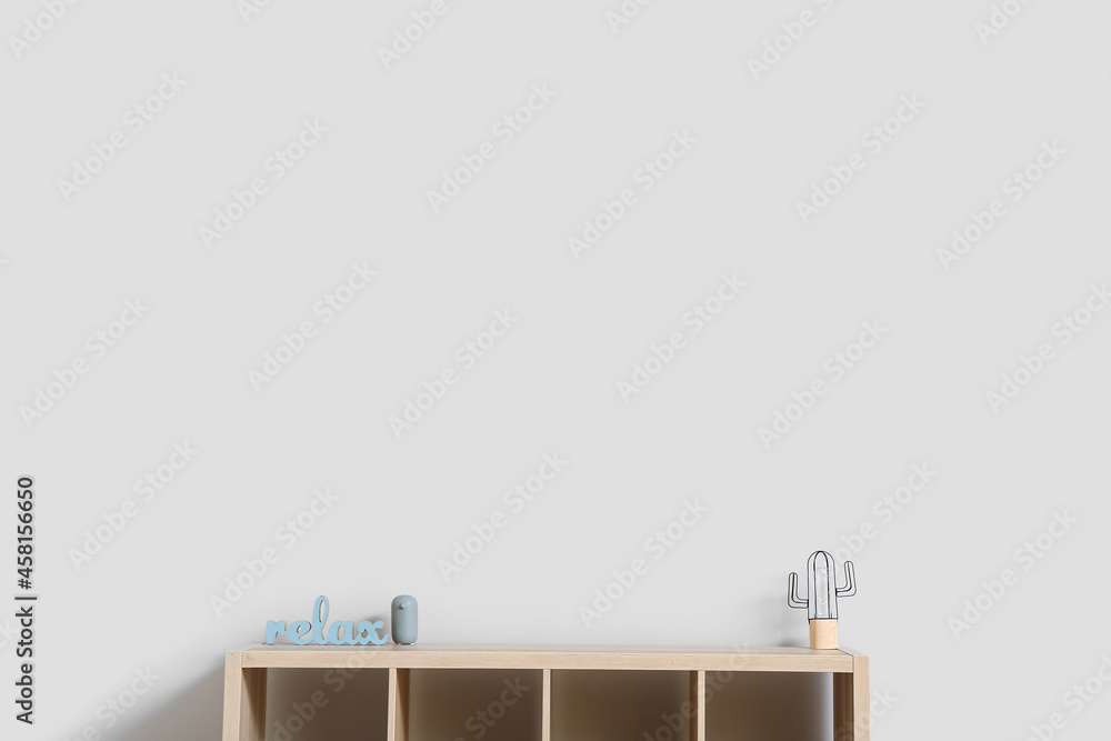 Modern wooden TV stand with lamp and decor near light wall