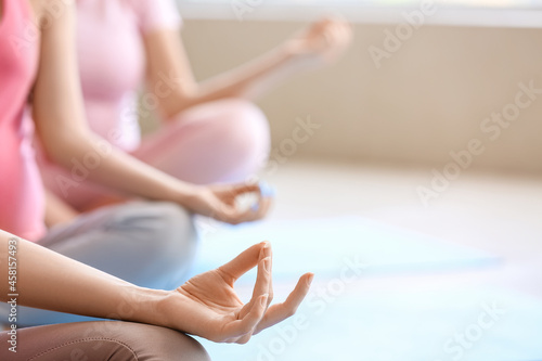 Young pregnant women practicing yoga at gym, closeup