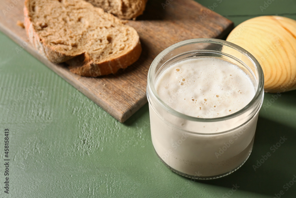Glass jar with sourdough on green wooden background Glass jar with sourdough on green wooden background