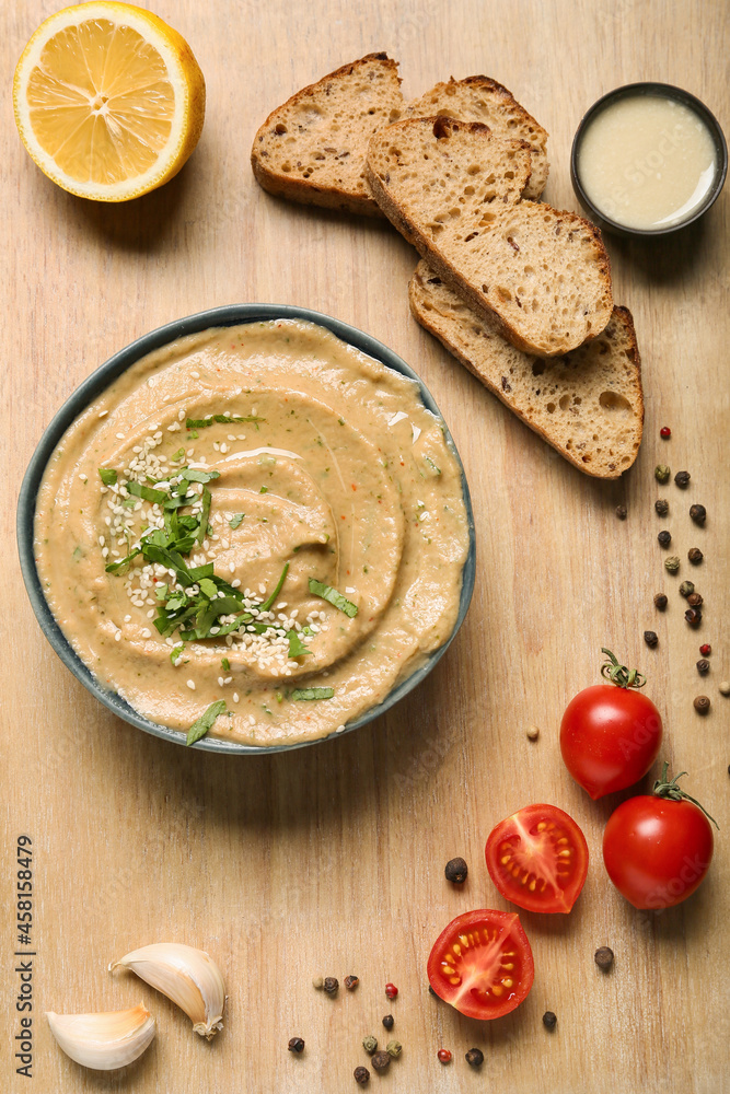 Bowl with tasty baba ghanoush, bread, lemon and tomato on wooden background