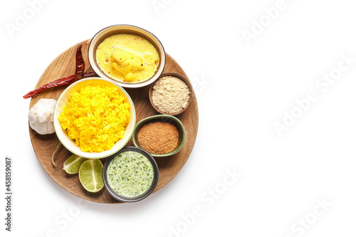 Tray with traditional Indian food and spices on white background