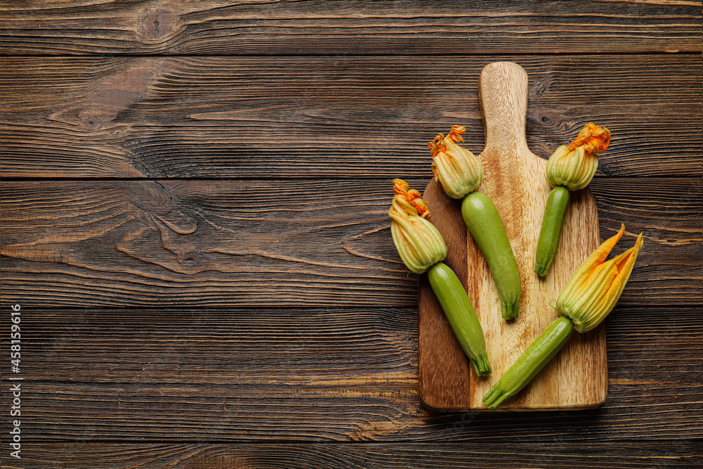 Board with fresh zucchini and flowers on wooden background Board with fresh zucchini and flowers on wooden background