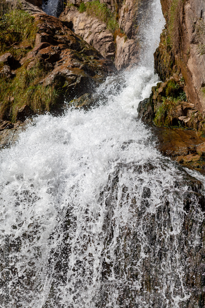 Close-up of a powerful waterfall in high quality. Side view of a sun-drenched waterfall in the wild. A large stream of water pours down from the mountain. Close-up of a powerful waterfall in high quality. Side view of a sun-drenched waterfall in the wild. A large stream of water pours down from the mountain.