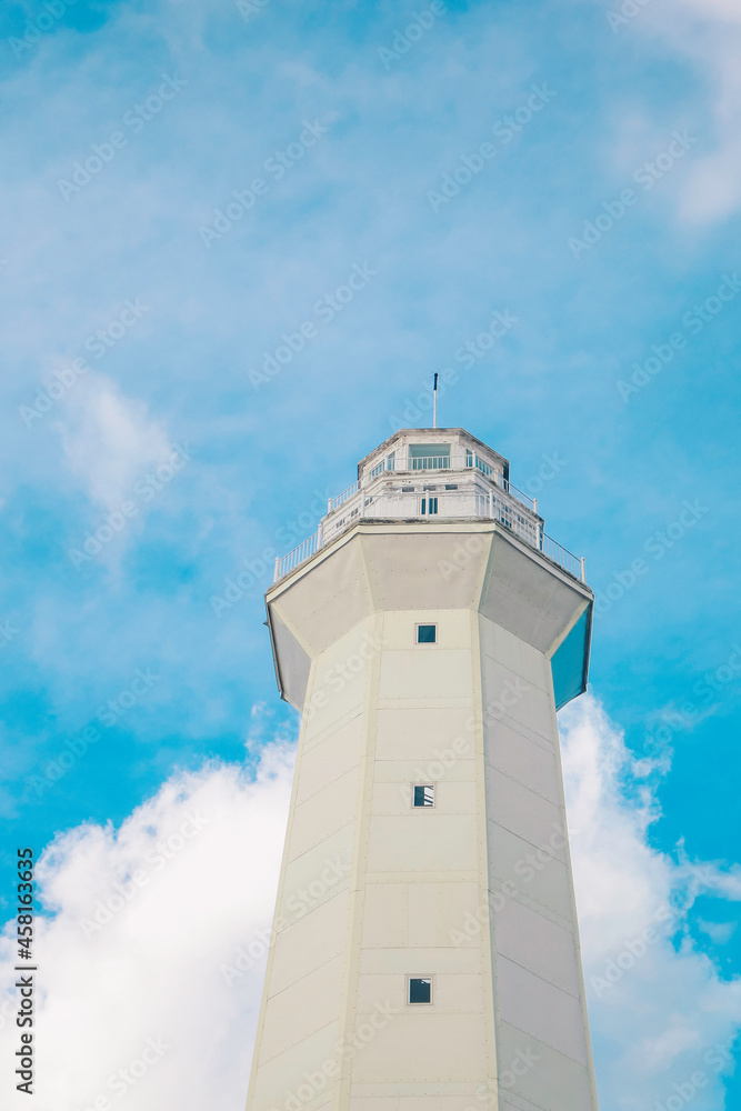 White Lighthouse against blue sky with white clouds on Rote Island, Indonesia.