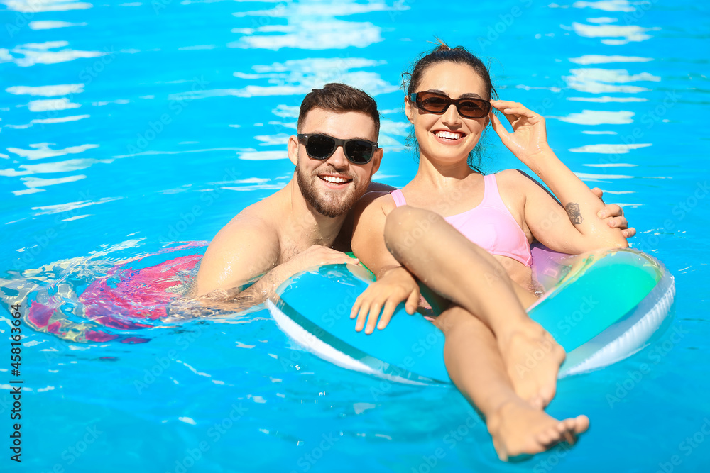 Young couple with inflatable ring in swimming pool
