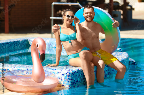 Young couple with inflatable rings in swimming pool © Pixel-Shot