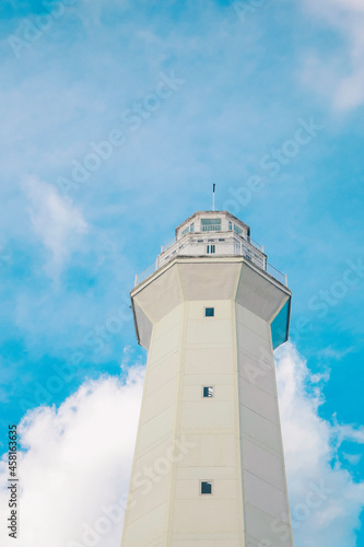 White Lighthouse against blue sky with white clouds on Rote Island, Indonesia.