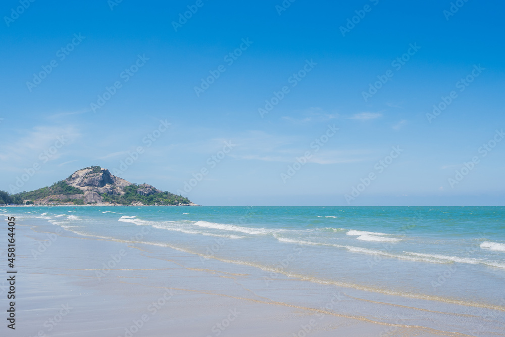 Emerald sea wave and white boiling foam surf on the tropical sandy beach with clear cloud and blue bright sky background in summer