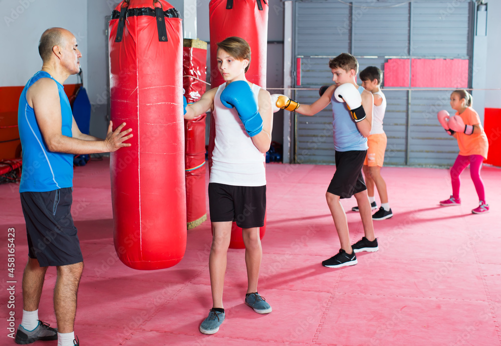 Boys and girl perform exercises in boxing training in a sports hall