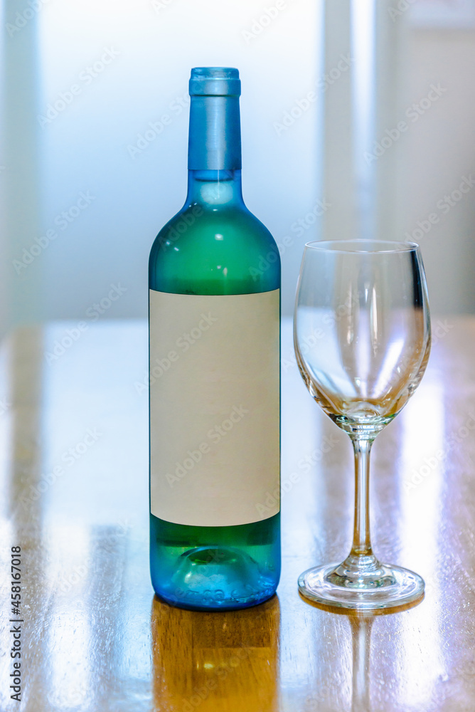 White wine bottele and glass on blurred window background White wine bottele and glass on blurred window background