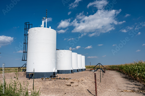 фотографія crude oil storage tanks with secondary containment and fencing in a rural corn f