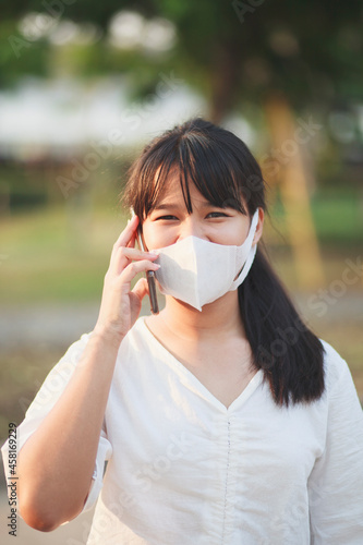 asian younger woman wearing protection mask talking on mobilephone