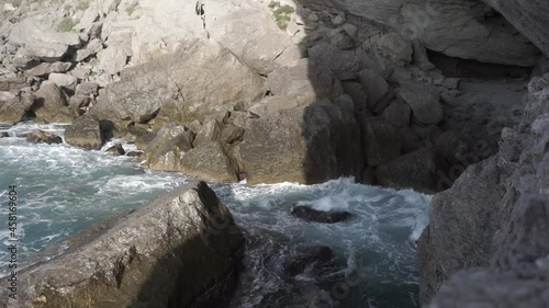 Footage. Water splashing. Pirate Bay Novy Svet Places. Mount Eagle is an ancient coral reef. Crimea. Sea water beats against rocks. Sea waves of blue-gray water beat against the coastal rocks.