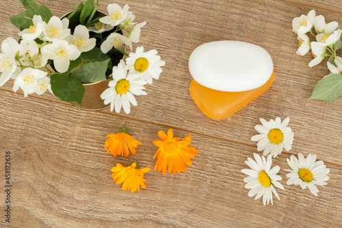 Yellow and white soap with flowers on wooden boards.