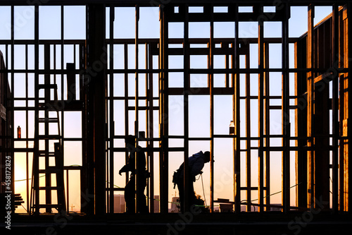 Framing carpenters building walls silhouetted by morning sunlight