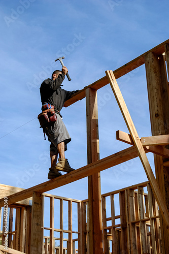 Carpenter framing a stud wall high on a scaffold