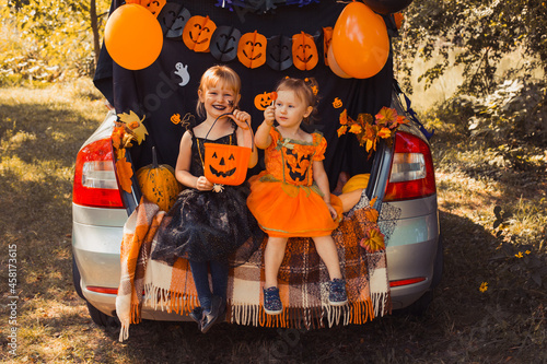 Children celebrating Halloween in trunk of car.