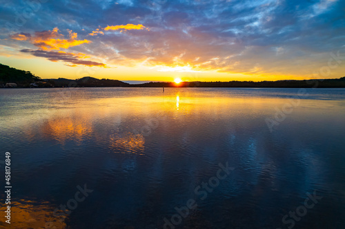 Sunrise waterscape and reflections with clouds © Merrillie