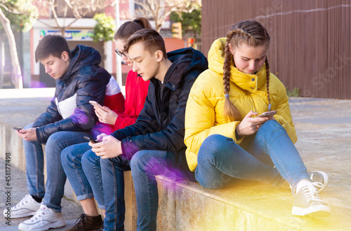 Modern teenagers spending free time outdoor absorbed in online communication. Concept of youth addiction of social networks
