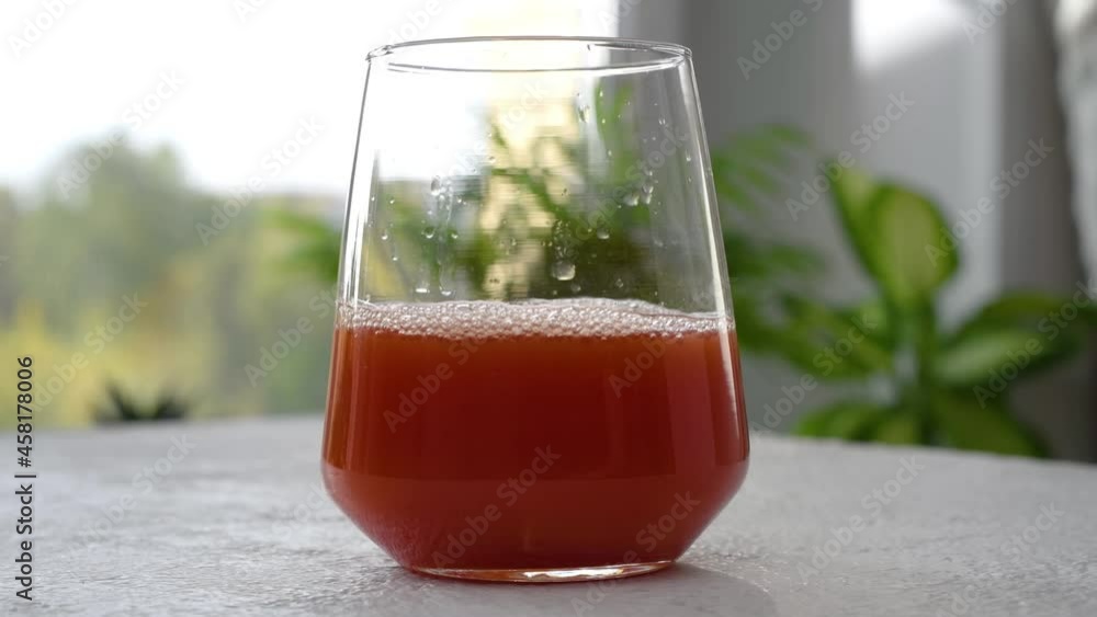 Tomato juice is poured into a glass. The camera moves around. Parallax effect. Close-up footage.