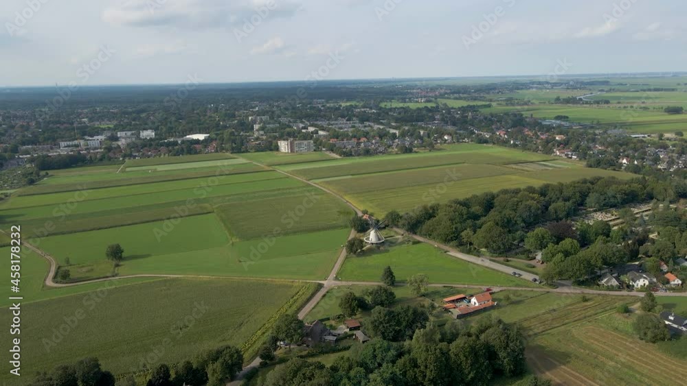 Flying towards spinning windmill in beautiful green rural town Flying towards spinning windmill in beautiful green rural town