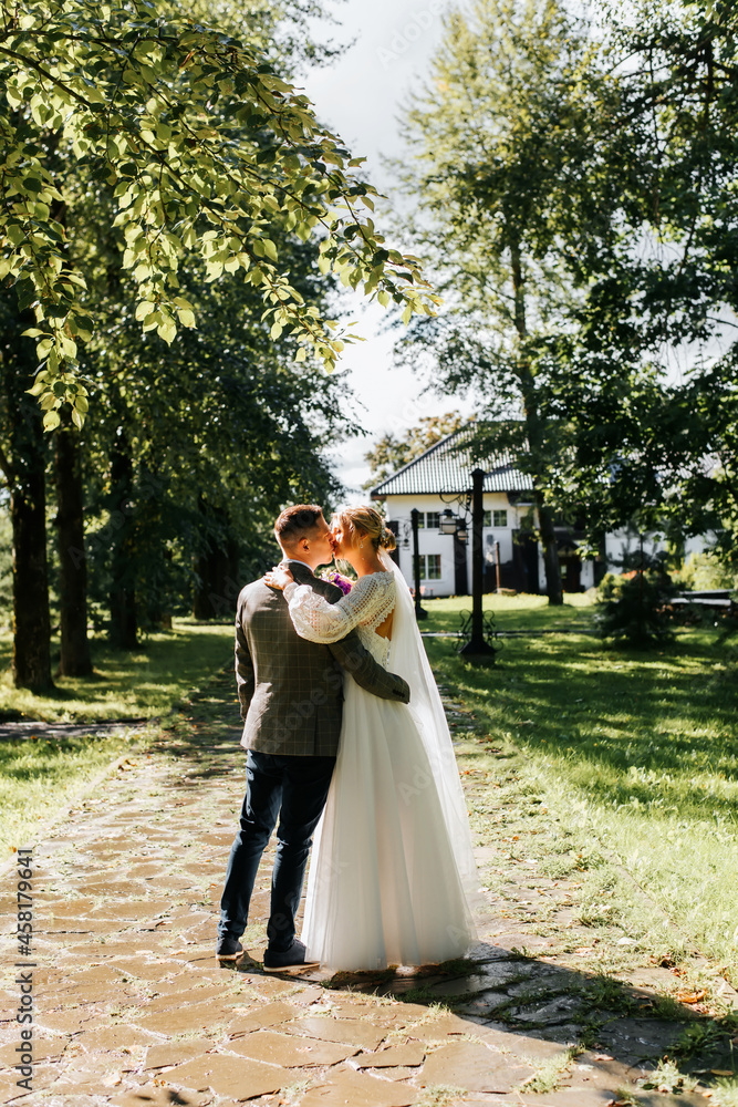 Wedding day. Beautiful young couple hugs on ranch, groom kisses bride in white dress with veil, kissing two loving married people outdoors. Marriage, wedding ceremony concept Wedding day. Beautiful young couple hugs on ranch, groom kisses bride in white dress with veil, kissing two loving married people outdoors. Marriage, wedding ceremony concept