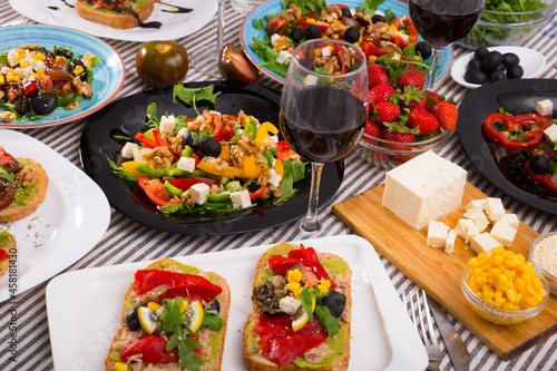 Top view of many plates with different vegetarian food and glass of wine