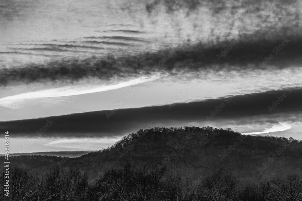 winter evening landscape with hills and cloudy sky, black and white photo
