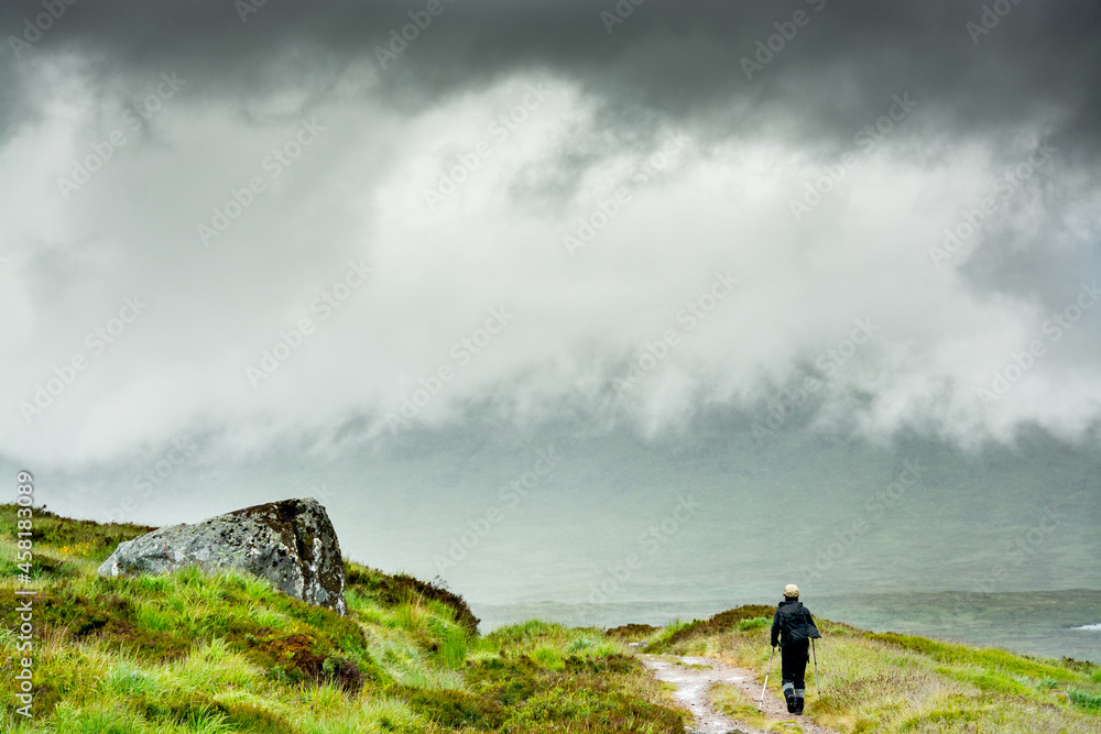 Along the West highland Way in Scotland. A female hiker walks on the old military road that arrives in the Glen Coe Valley