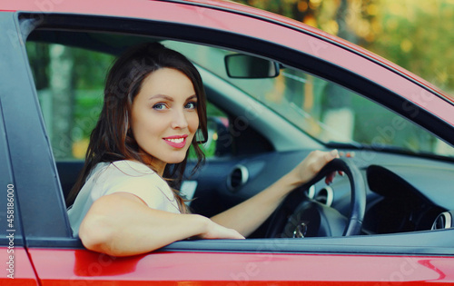 Smiling woman driver behind a wheel red car