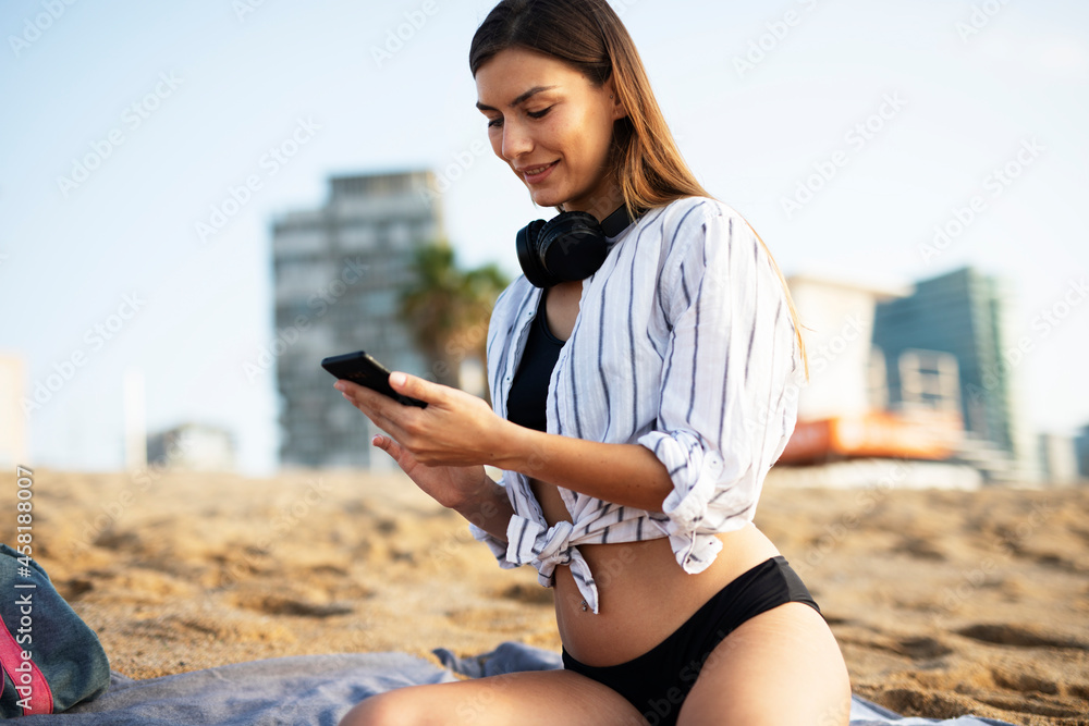 Happy young woman relaxing on the sandy beach. Beautiful woman listening the music..