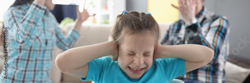 Llittle girl in fear closes her ears so as not to hear her parents swear