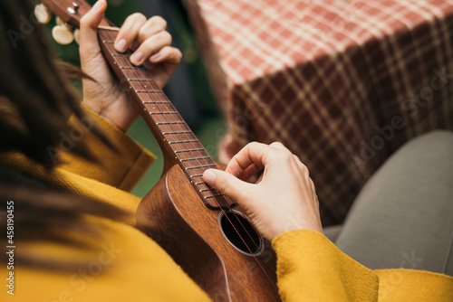 girl with dreadlocks closeup playing an acoustic instrument ukulele in autumn on the terrace photo