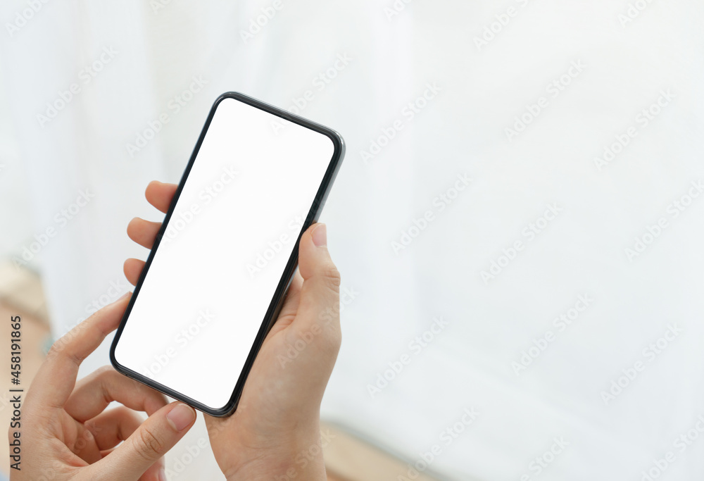 Close up of hand holding smartphone with white mock-up screen.