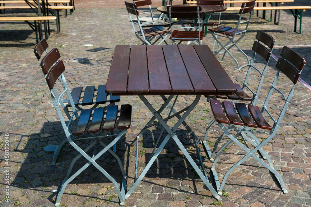 Leere Tische und Stühle im Außenbereich einer Gastronomie auf einem Platz - selektiver Fokus Leere Tische und Stühle im Außenbereich einer Gastronomie auf einem Platz - selektiver Fokus