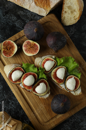 Concept of tasty food with bruschetta with fig on black smokey table