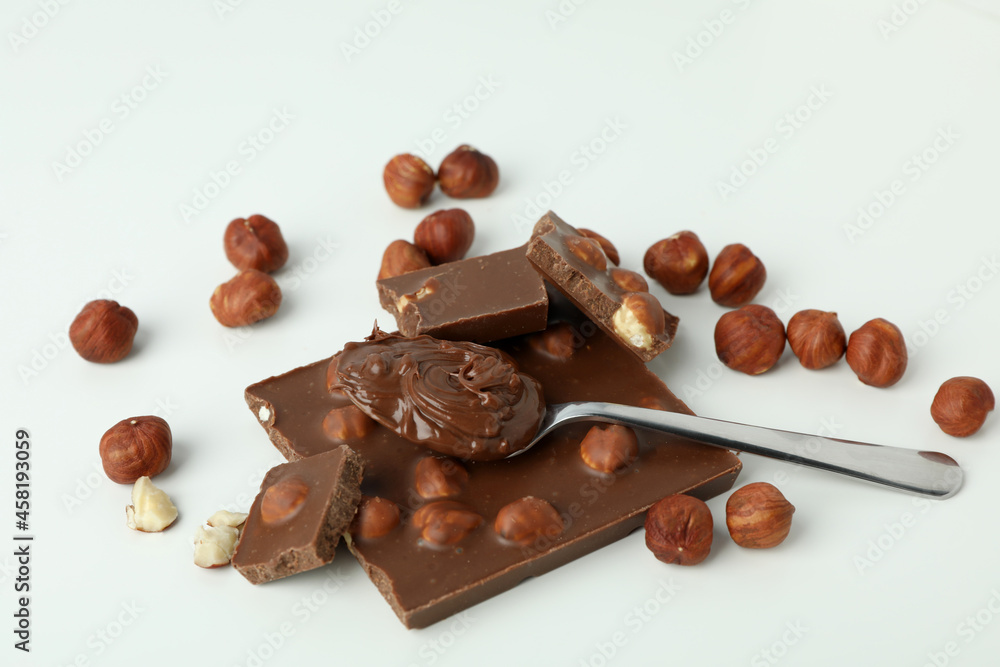 Spoon with chocolate paste and chocolate with nuts on white background