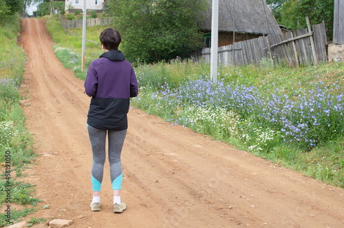 A girl standing on a rural road and looking into the distance