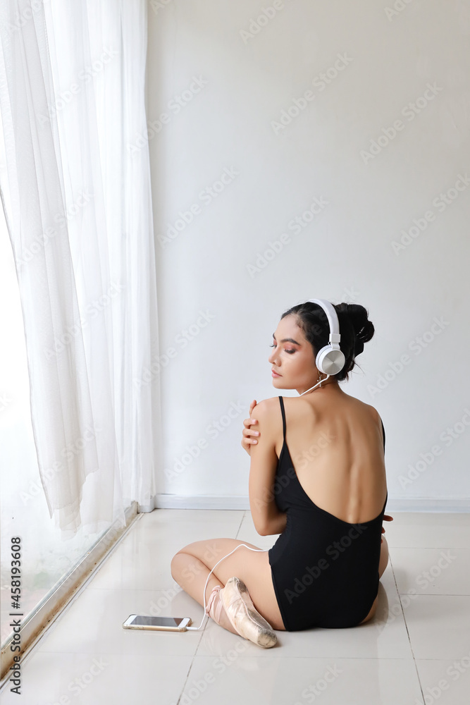 full length beautiful healthy and sporty asian young woman in black sportswear with headphone, listening music from mobile phone while training ballet dancing. full length beautiful healthy and sporty asian young woman in black sportswear with headphone, listening music from mobile phone while training ballet dancing.