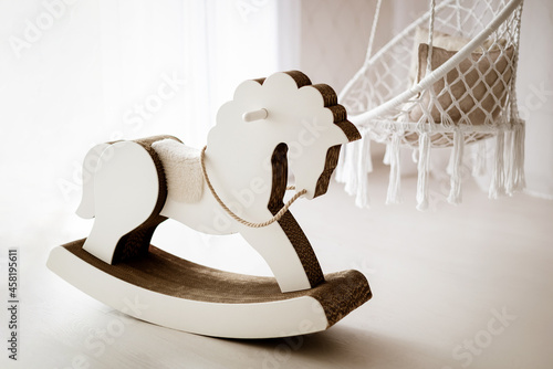 Light interior of children's room with wicker swings and white toy rocking horse photo